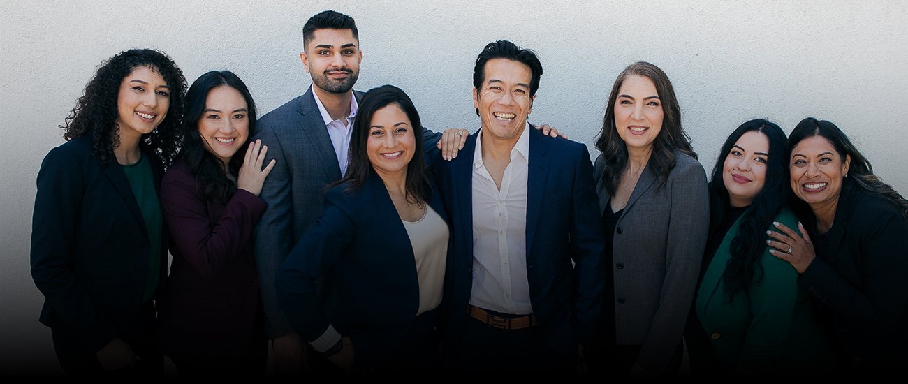 All eight members of the firm, photographed together against a light stucco wall.